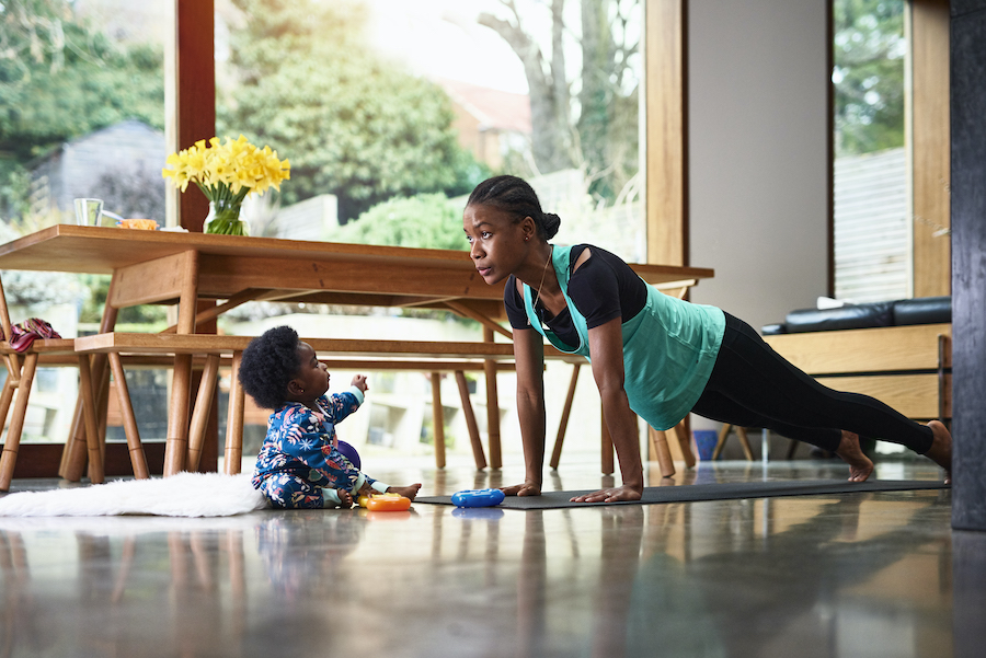 young mother doing yoga with baby looking up at her 