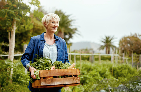 Woman carrying box of produce in a garden